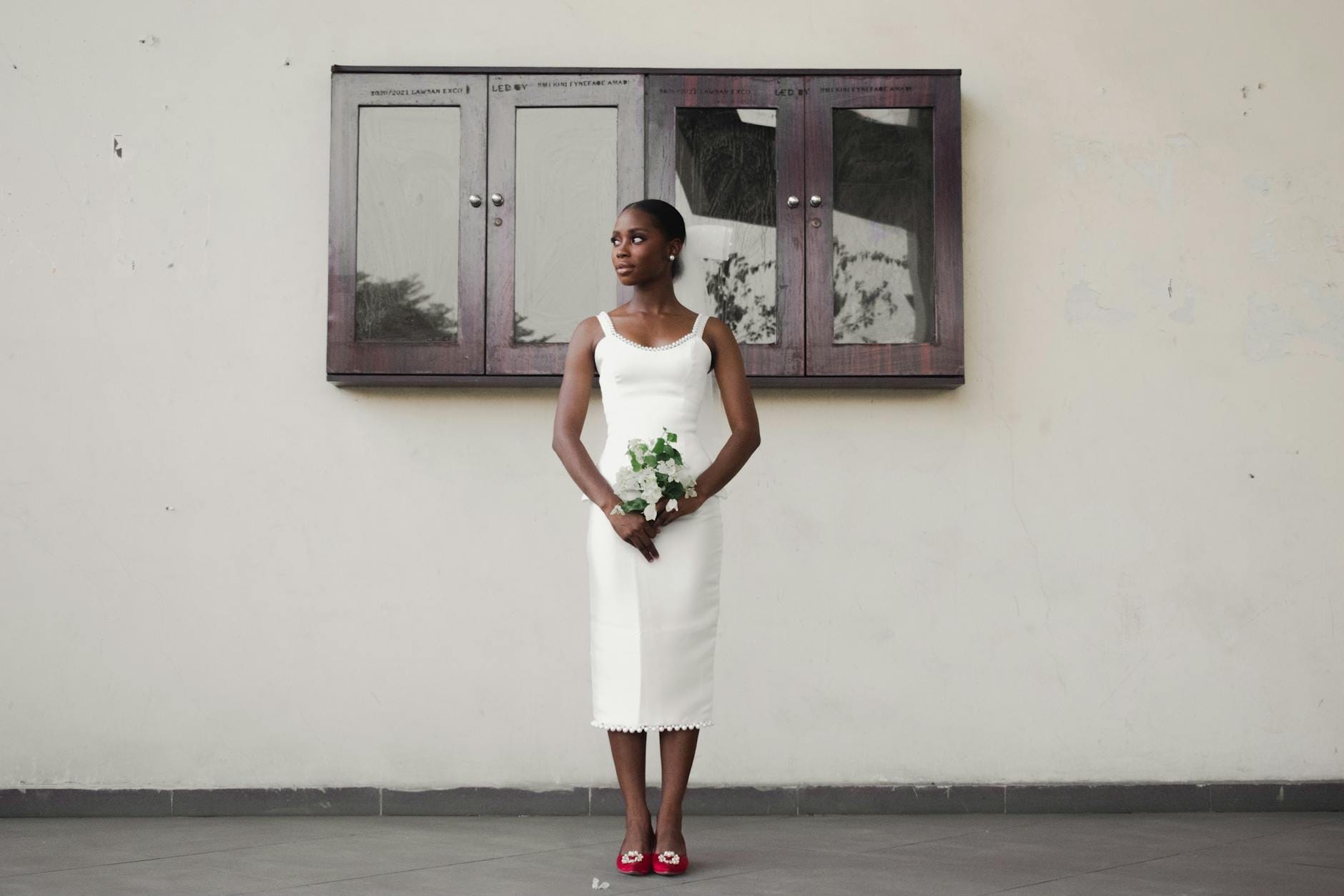 Panna młoda w prostej białej sukni ślubnej z bukietem na tle wnętrza