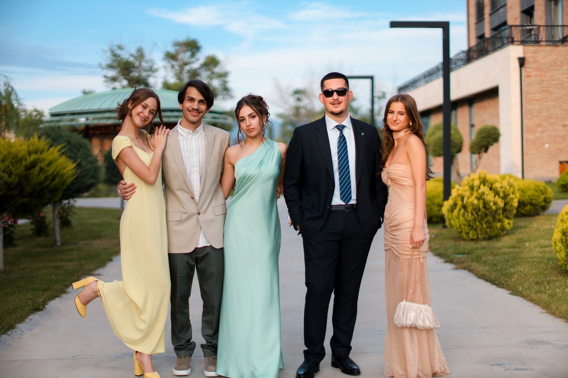 Młodzi dorośli w eleganckich sukienkach i garniturach na zewnątrz Młodzi dorośli w eleganckich sukienkach i garniturach na zewnątrz