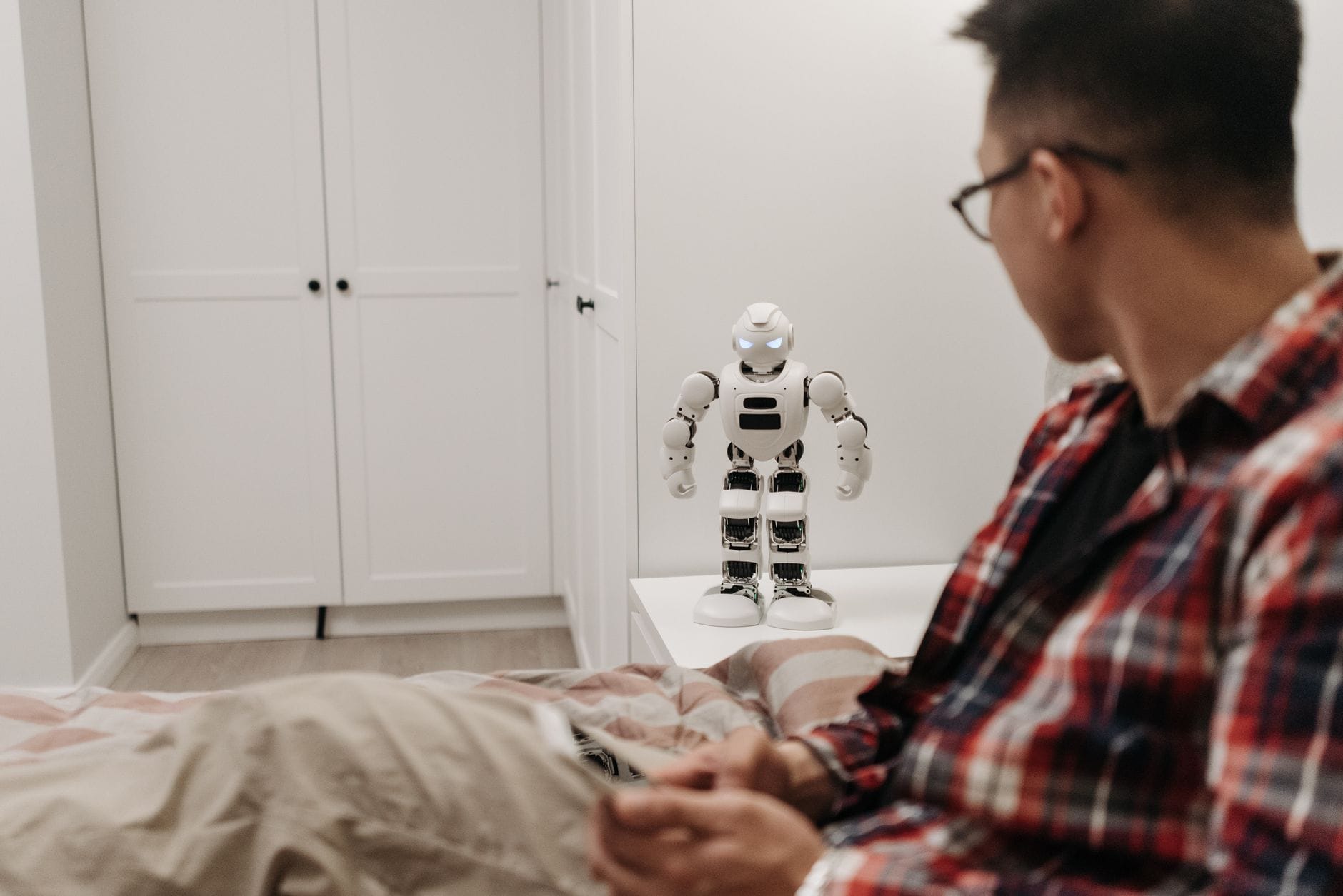 Mężczyzna bada robota na stole w nowoczesnej sypialni